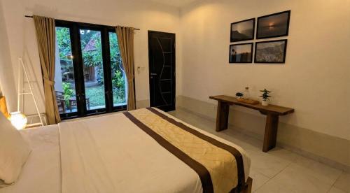 a bedroom with a bed and a table and a window at Room #3 Mari Posa Cottage in Badung