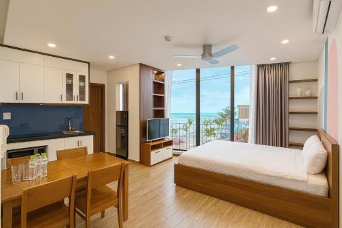 a bedroom with a bed and a table and a kitchen at Anstay Beach Da Nang in Danang
