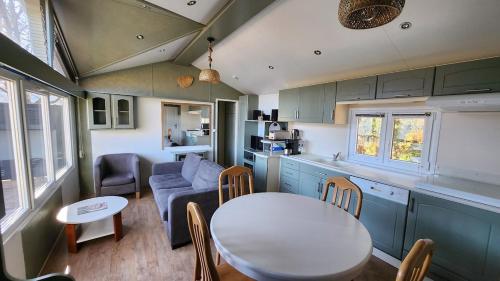 eine Küche und ein Wohnzimmer mit einem Tisch und einer Couch in der Unterkunft La perle du lac - Némausa location in Chorges