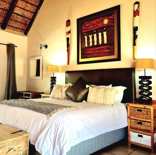 a bedroom with a large bed with white sheets at Nzenga Lodge in Hoedspruit