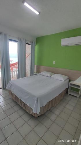 Un dormitorio con una cama grande con una pared verde. en Flats Privé Village Galés, en Maragogi