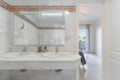 Un baño blanco con dos lavabos y un espejo. en 3 bedroom townhouse close to the beach, en Estepona