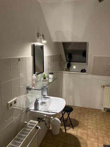 a white bathroom with a sink and a chair at FEWO-Wölkchen mit Ausblick & Komfort über den Dächern von Weißenfels in Weißenfels