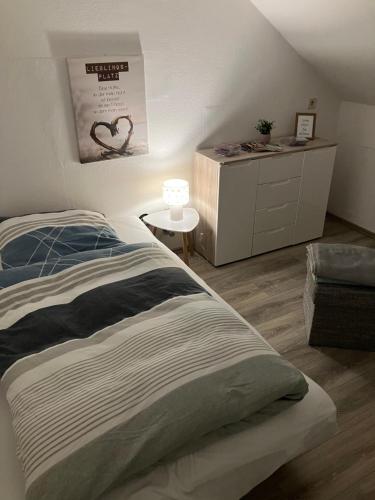 a bedroom with a bed and a dresser with a lamp at FEWO-Wölkchen mit Ausblick & Komfort über den Dächern von Weißenfels in Weißenfels