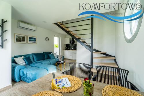 a living room with a blue couch and a table at Domek w Baltic Natur Park Komfortowy 2 sypialnie klima alpaki mnóstwo atrakcji by DG in Niechorze