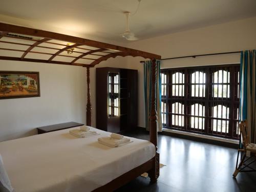 a bedroom with a bed with white sheets and windows at Seashore Beach Resort Varkala in Varkala