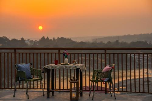 a table and chairs on a balcony with the sunset at LiveAway Rishikesh, Laxman Jhula by PACK in Rishīkesh