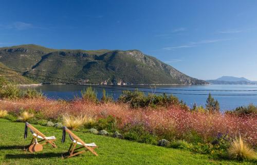 two wooden benches sitting in the grass near a body of water at Amber by the sea in Évyiros