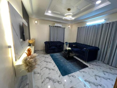 a living room with blue couches and a marble floor at Premium House Kouritenga ISPP in Ouagadougou