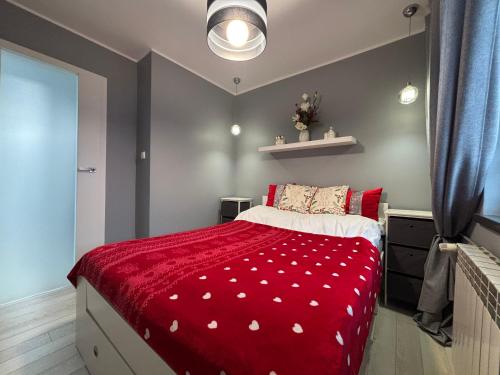 a bedroom with a bed with a red comforter at Ekskluzywny Apartament Joanna w centrum Bochni in Bochnia