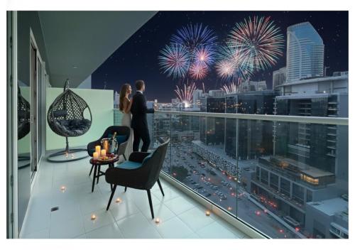 a man and a woman standing on a balcony with fireworks at Luxury 1-Bedroom Apartment with Pool, Gym & Balcony in Business Bay in Dubai