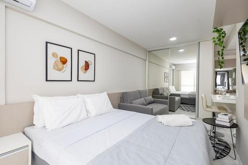 a white bedroom with a large bed and a couch at Edifício Champagnat Office in Curitiba