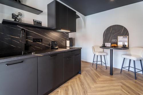 a kitchen with black cabinets and a table with chairs at Saga - Cinema Room in Chagny
