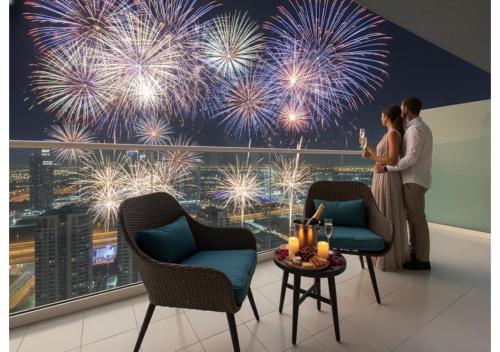 a couple standing in front of a fireworks mural at Luxury 1-Bedroom Apartment with Pool, Gym & Balcony in Business Bay in Dubai