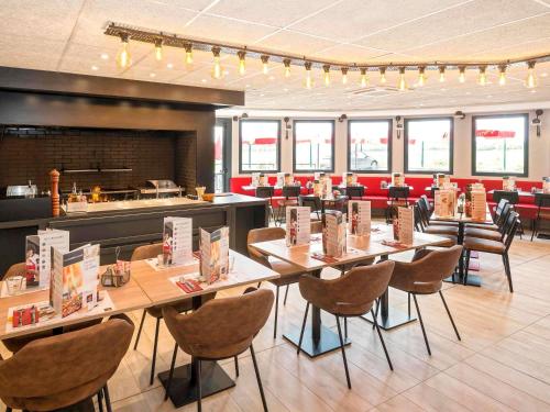 ein Restaurant mit Holztischen und Stühlen und einer Theke in der Unterkunft ibis Pontorson Baie Du Mont Saint Michel in Saint-Georges-de-Gréhaigne