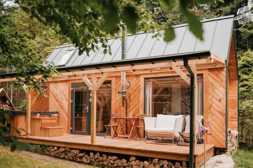 Tiny house nad potokiem في Ohłypów: منزل صغير مع شرفة وكراسي