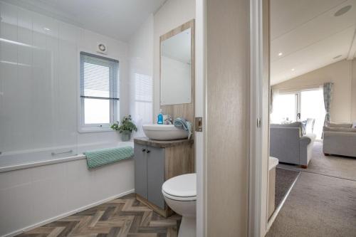 a bathroom with a toilet and a sink and a mirror at Sea Dreams, Riviera Bay - Brixham in Brixham