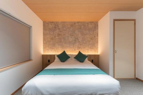 a bedroom with a large white bed with green pillows at Ubaku Villa 美瑛一棟貸し別荘 Private Nature Retreat in Biei Hokkaido in Biei