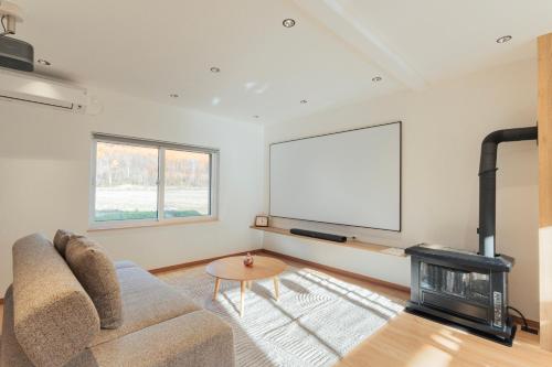 a living room with a couch and a flat screen tv at Ubaku Villa 宇莫別荘 in Biei