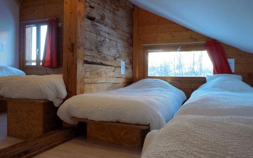 a bedroom with three beds in a log cabin at Auberge de Jeunesse HI La Clusaz in La Clusaz