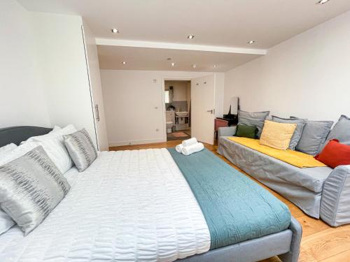 a bedroom with a large bed and a couch at Modern 3-Bedroom flat in Holloway with Private Patio near Islington, Caledonian Road, Emirates Stadium by Staylio Ltd in London