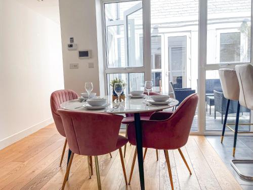 a dining room table and chairs with wine glasses on it at Modern 3-Bedroom flat in Holloway with Private Patio near Islington, Caledonian Road, Emirates Stadium by Staylio Ltd in London