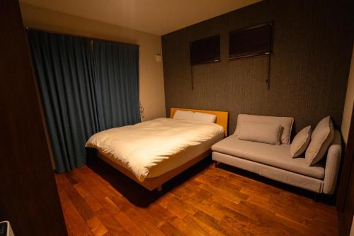 a small bedroom with a bed and a couch at 癒しの宿 古紗庵 in Minakami