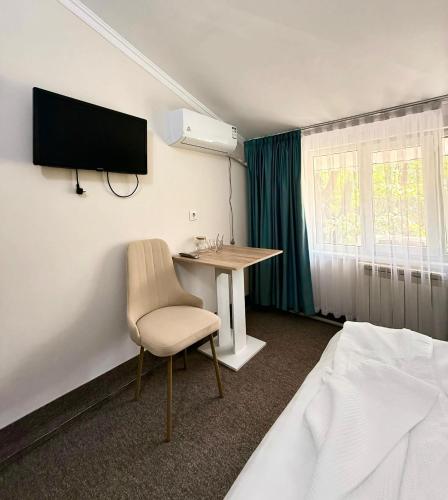 a hotel room with a desk and a tv on the wall at GRAND Hotel in Almaty