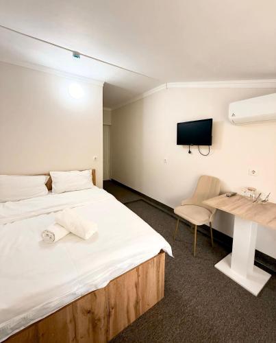 a bedroom with a bed and a desk and a tv at GRAND Hotel in Almaty