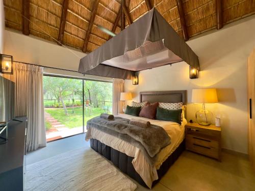 a bedroom with a large bed and a large window at Wildlife Estate Villa - Pool - Boma - Bushlife in Hoedspruit