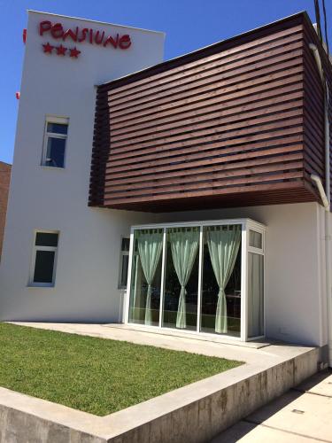 a white building with a large window with curtains at Pensiunea Play in Deva