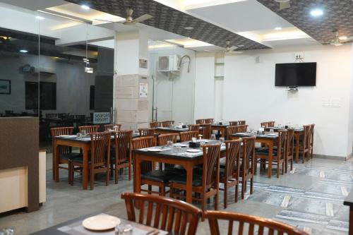 een eetkamer met tafels en stoelen en een tv bij SeaFORT Beach Resort in Murūd
