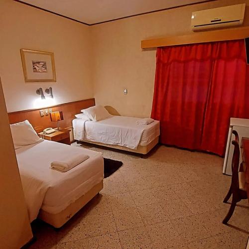 um quarto de hotel com duas camas e uma cortina vermelha em GRAN Parana SUITES HOTEL Asunción Centro em Assunção