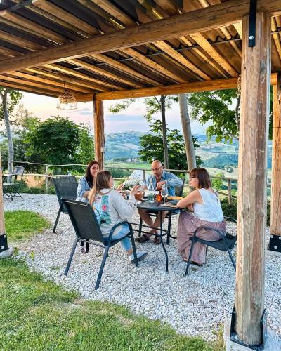 a group of people sitting at a table under a pergola at Glamping & country house Marche Nascoste Gualdo in San Girolamo di Sopra