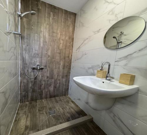 Un baño con lavabo y ducha con espejo. en Guest house LORA, en Gabrovo