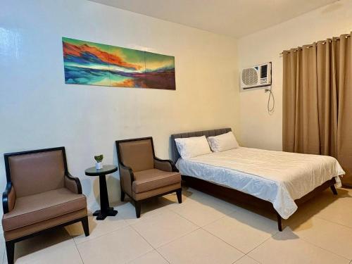 a bedroom with a bed and two chairs in it at The Infinity Condominium BGC at high Street in Sampong