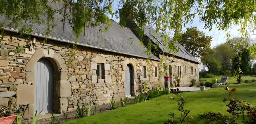 an old stone building with a grass yard next to it at Escapade Bretonne in Rospez