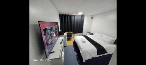 a hotel room with a bed and a flat screen tv at AwayHome Guest Rooms in London
