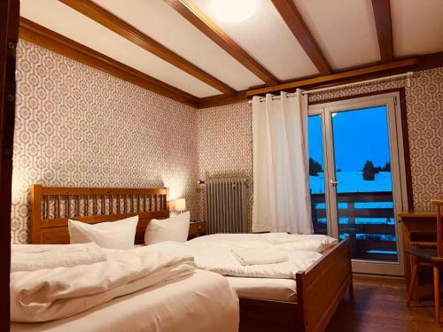 a bedroom with two beds and a large window at Berggasthaus Auerhahn - Ski In- Ski Out- in Feldberg