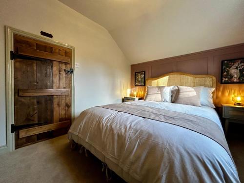 a bedroom with a large bed and a wooden door at Daisy Cottage - Framlingham in Framlingham