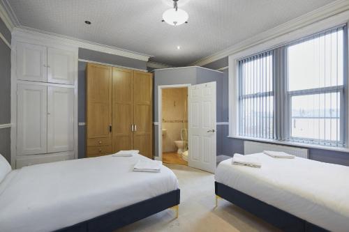 a bedroom with two beds and a bathroom at Hayy Contractor House 5 Bedroom Huddersfield Sleeps 18 in Huddersfield