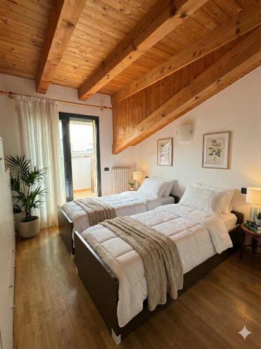 two beds in a bedroom with wooden ceilings at Marconi Deluxe - Attico a Due Passi dal Mare in Lido di Jesolo