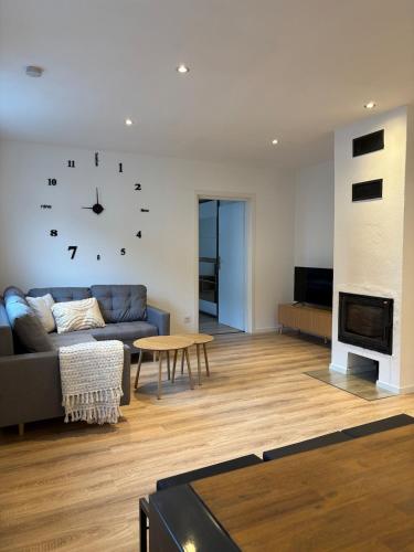 a living room with a couch and a clock on the wall at Modern apartment with feel-good factor in Gravenwerth