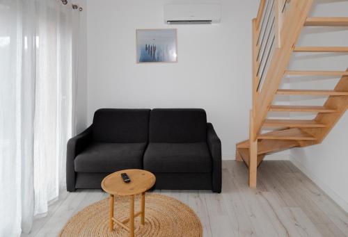 a living room with a black couch and a wooden stool at Les Cottages de Ripaille in Thonon-les-Bains