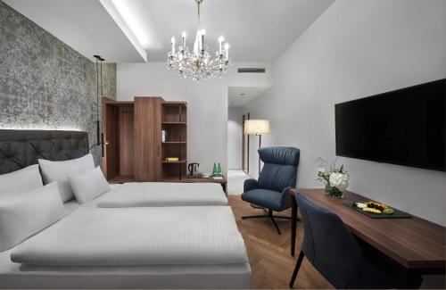 a bedroom with a bed and a desk and a tv at Hotel Schwarzer Adler Innsbruck in Innsbruck