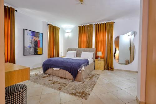 Lagos Residence - Luxury 4Bedroom Apartment Ikoyi في لاغوس: غرفة نوم بسرير كبير مع ستائر برتقالية