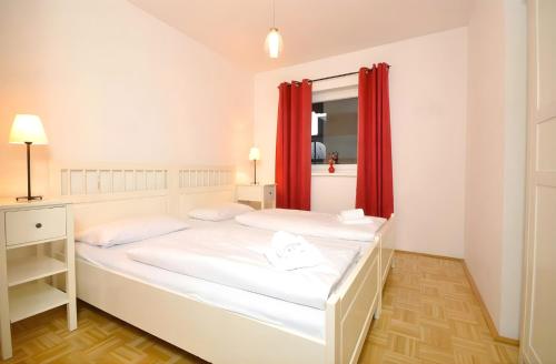 two beds in a room with red curtains at Kitzsteinhorn Kaprun Panorama in Dürnberg