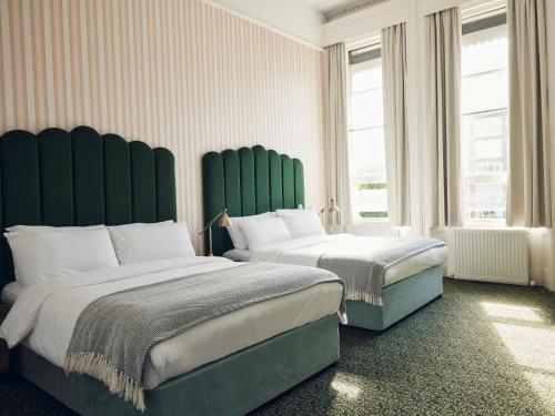 a bedroom with two beds with green headboards at The Columbia in London