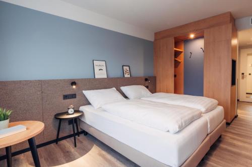 a bedroom with a large white bed and a table at harry's home Salzburg in Salzburg