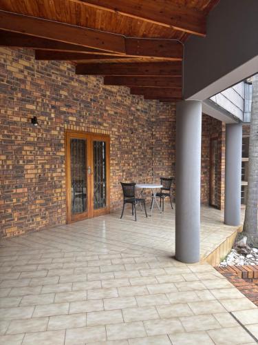 a patio with a table and chairs and a brick wall at Spacious 7 bedroom house with pool and jacuzzi in Johannesburg